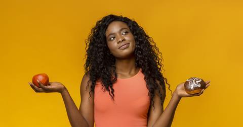 A woman with an apple and doughnut in her hands