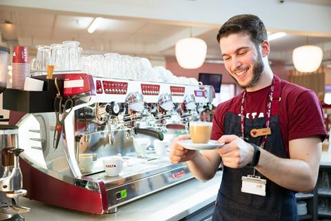 Costa Coffee staff smiling holding a coffee
