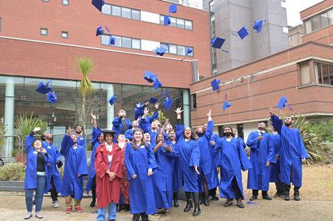 Students in blue robes throwing their hats into the air