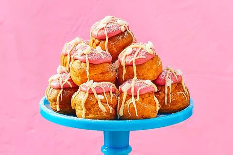 Profiteroles with pink fondant and white chocolate on a blue cake stand