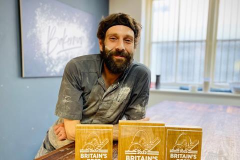 A baker with a dark beard with flour on his face