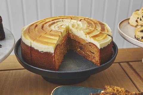 A sticky toffee cake with white chocolate frosting and a slice taken out of it