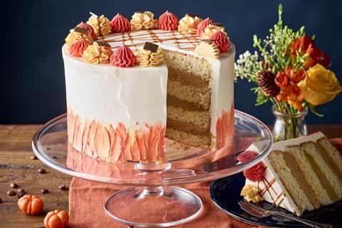 A four layer cake with white buttercream and red and cream decorations