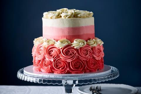 A two tiered cake with pink ombre frosting and rosettes of frosting