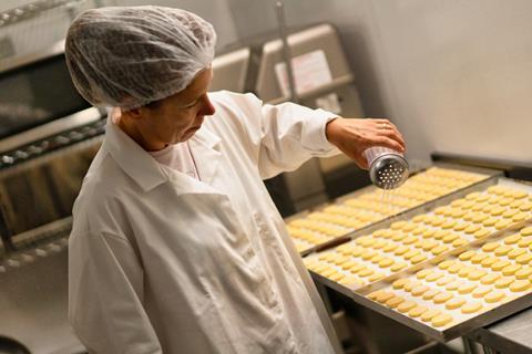 A worker applies a sugar dusting to products at Studio Bakery in Clitheroe, Lancashire