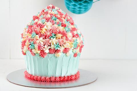 A giant cupcake decorated with white, blue and pink frosting