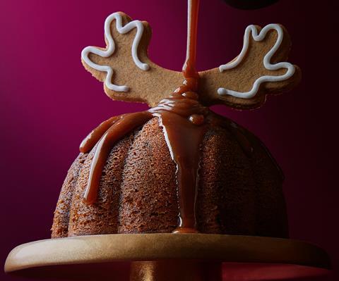 A Sticky Toffee Gingerbread Pudding with gingerbread reindeer antlers on top and a toffee sauce being drizzled over it
