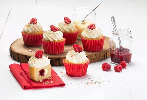 Four cupcakes in red cases with whipped cream and raspberries on top