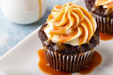 A sticky toffee cupcake with swirls of frosting and sauce on top