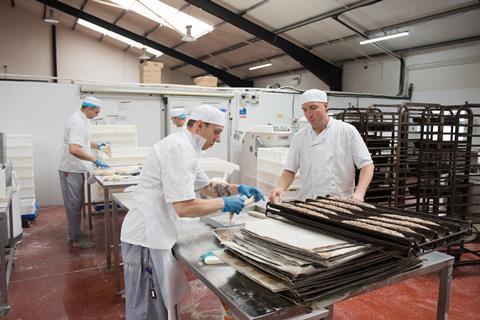 Bakers in white coats and hats in a bakery