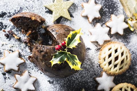 A Christmas pudding, mince pie, and Christmas biscuits on a grey slate board