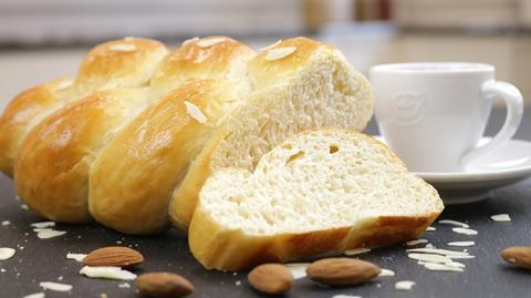 A plaited white loaf next to a white coffee cup