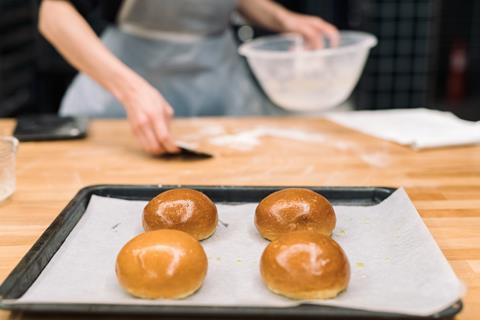 Four glossy brioche buns on a baking tray