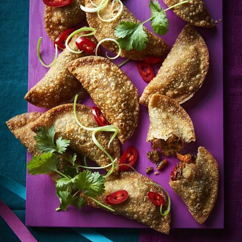 Empanadas, fried pastry on a board with chilli and herbs