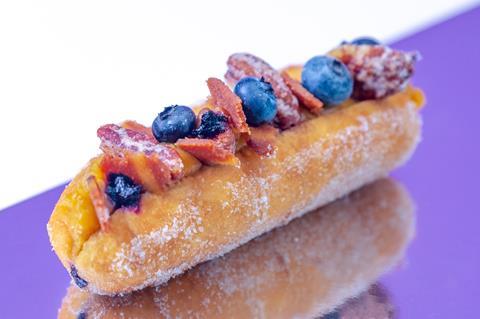 A finger doughnut with vegan bacon, blueberries and candied pecans on top