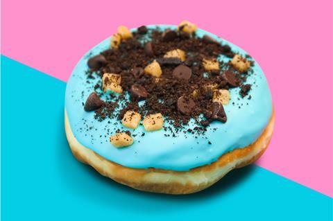 A doughnut with blue icing, chocolate biscuit crumb and cookie dough pieces on top