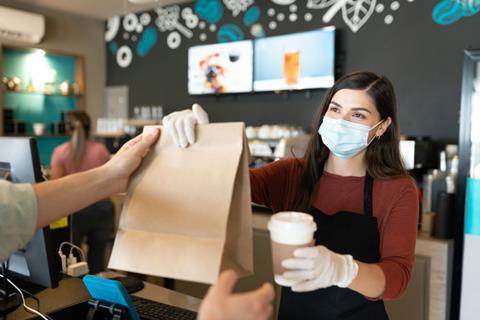 Woman serving takeaway coffee and food in brown bag