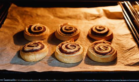 Cinnamon buns on baking paper and tray in the oven