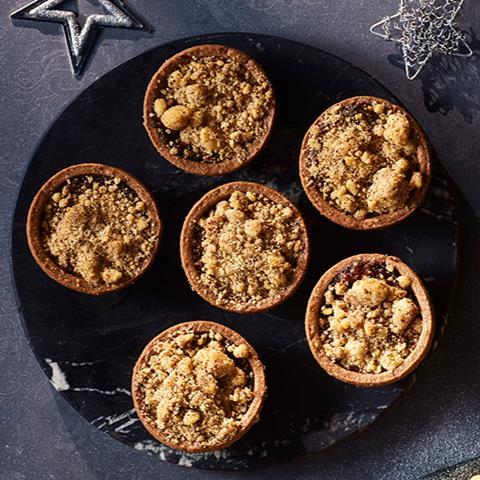 Six cherry and chocolate crumble topped mince pies on a black plate