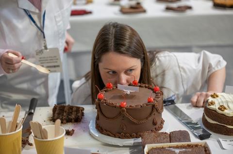 A judge inspects The Chocolate Cake by Abba Cakes during Britain's Best Cake 2025 at the NEC Birmingham