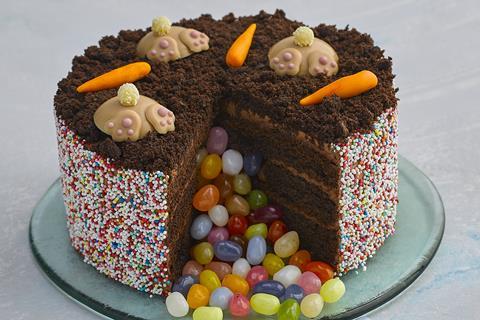 An Easter themed chocolate pinata cake with edible bunny bottoms, carrots on top and jelly beans pouring out