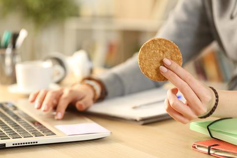 A woman eating a biscuit at a desk