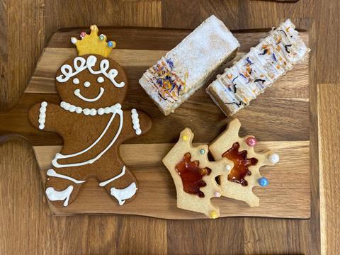 A gingerbread biscuit with crown on, cake slices and crown biscuits