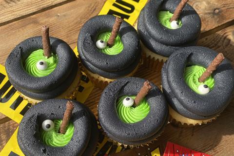 Cauldron Cupcakes with a swirl of black frosting on top and edible broomhandle sticking out