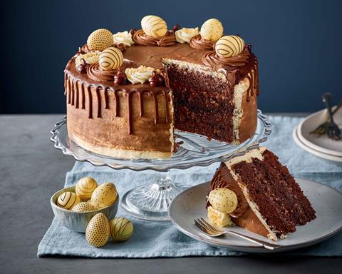 A chocolate layer cake with dark chocolate drip and white chocolate eggs on top