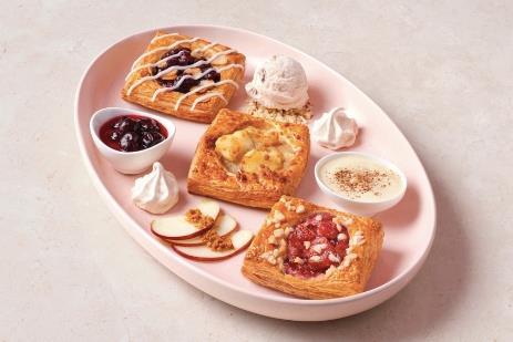 Three fruit Danish pastries on an oval plate on a pink background